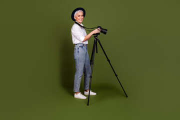 Full length photo of attractive elderly lady photographer dressed white shirt cap filming camera...