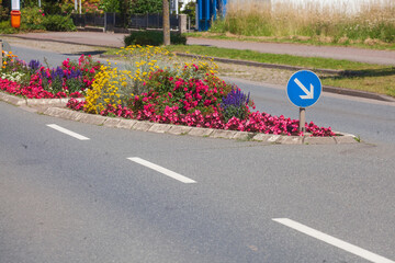 Verkehrsinsel auf Straße mit Pfeilwegweiser und  Blumenbeet, Deutschland