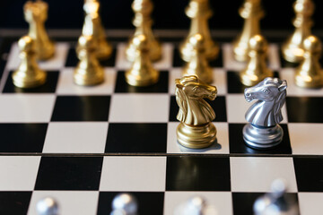 Closeup shot of chess knights placed on chessboard in front of each other representing competition...