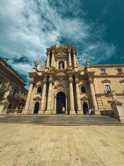 Obraz premium A large church with a clock tower and a cross on top. The building is surrounded by a courtyard