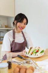 Asian women holding plate of delicious sandwich after making sandwich with boiled egg salad and fresh vegetable while cooking breakfast meal and making healthy food lifestyle in the kitchen at home