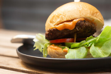 Close-up Hamburger with meat, pickles and ketchup in disk on wooden table.