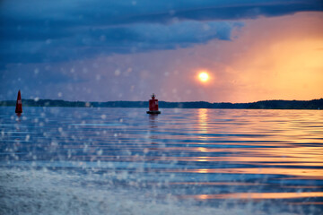 Fototapeta premium A view of the wave from the boat on the river and the pink and orange sky at sunset with clouds with the reflection of the sun in the river 