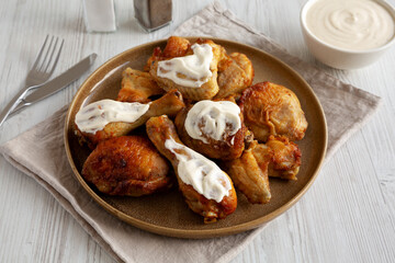 Homemade BBQ Chicken Drumsticks and Wings with Alabama White Sauce, side view.