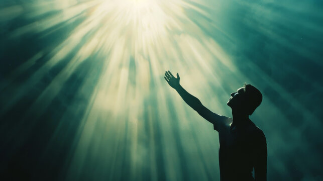 A man reaches towards beams of light piercing through mist, symbolizing hope, inspiration, and a connection to the divine or higher self.