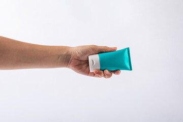 Blue cosmetic bottle, Skin care or sunscreen cosmetic in hand on white background.