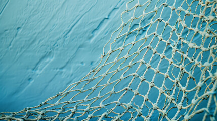 A detailed close-up of a fishing net draped against a textured, blue background, creating a nautical and serene setting, evoking a sense of calm. © VK Studio
