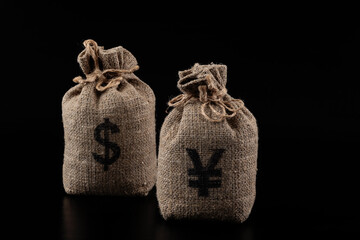 Money bags with US dollar and Chinese yuan symbols on black background