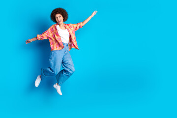 Full size photo of attractive young woman jump flying dressed stylish checkered clothes isolated on blue color background