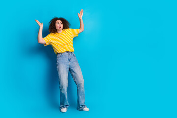 Full body photo of attractive young woman frightened look up empty space dressed striped yellow...