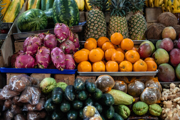 tropical fruits in a traditional market, including coconut, pitahaya, pineapple, mango, and ginger