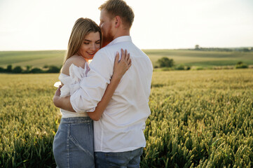 Closeness, embracing each other. Lovely couple are on the green agricultural field together