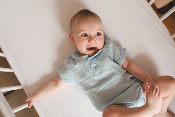 Sleepy baby boy 3-4 months old wake up in cot close up top view. Childhood. Good morning.