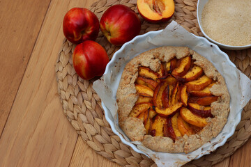 Homemade galette with peaches on wooden table. Baked french open pie with summer fruits
