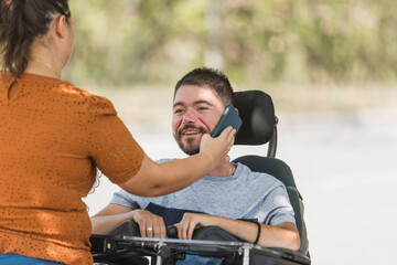 Female assistant helping a man in a wheelchair to use a smartphone. Disability and daily activity concepts.