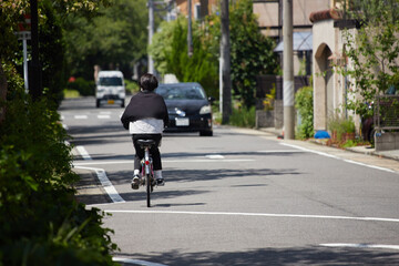 夏の街の道路で自転車を乗る女性の姿