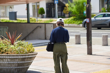 真夏の昼の都市の繁華街で歩く一人の若い女性の姿