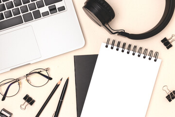 Workspace with laptop, eyeglasses and office supplies on a beige background. Business concept with empty notepad mockup.