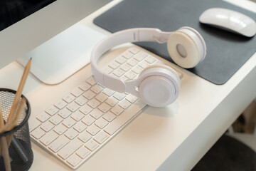 A work desk with Bluetooth headphones placed on it