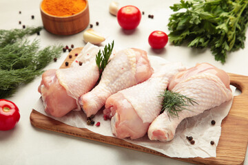 Raw chicken drumsticks with spices on cutting board on light background. Top view. Free space for...
