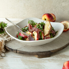 plate with salad with arugula, bresaola and peaches on the table