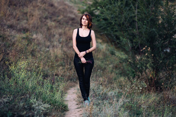 Boho hippie woman with flowers in her hands in nature outdoors on sunset near green hills