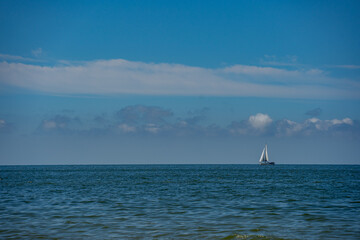 a lonely sailing ship at sea against a blue sky
