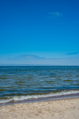 a lonely sailing ship at sea against a blue sky