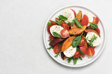 Peaches, tomatoes, mozzarella salad in plate on  white background. Caprese italian traditional salad top view