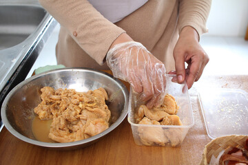 Close up of a person hand marinating chicken meat in metal bowl