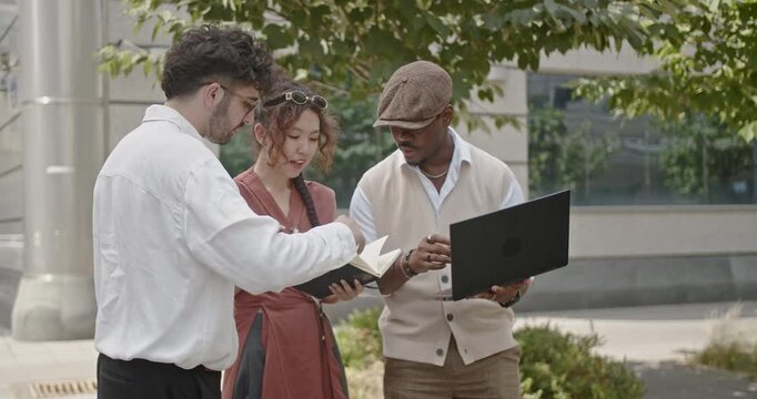 In a relaxed business meeting environment, a group of diverse colleagues collaborates outdoors with a laptop, sharing innovative ideas and discussing their project strategies.