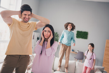 Fototapeta premium Photo of annoyed angry parents dressed casual clothes suffering children noise indoors house apartment room