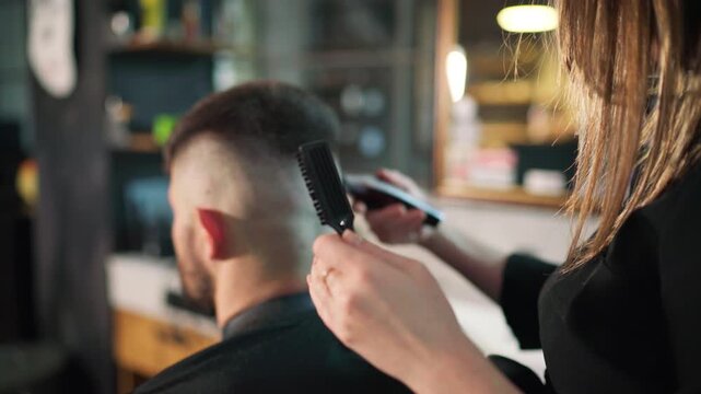Young female barber making men's undercut haircut hairstyle using Haircut Clipper in Modern style barber shop. Haircare service local small business, cosmetics and personal care industry 4K video