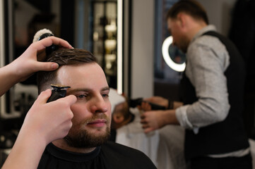 Haircut alignment of the contour of the head with trimmer. Short haircut in the barbershop.