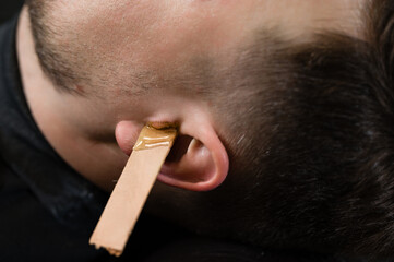 Hair removal procedure in a barbershop. Ear hair wax removal.
