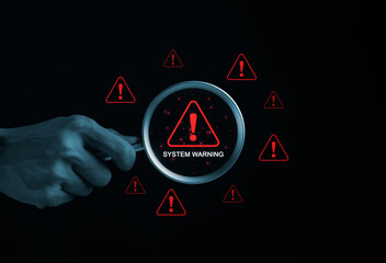 System Warning Alert, Cyber Security Concept. Hand holds magnifying glass over digital warning sign...