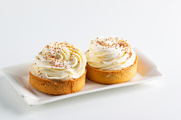 Lemon tartlets with whipped cream, sprinkles and chocolate chips on white background