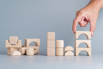 Closeup hand of a man manage the pile of wooden toy on the left into the similar group on the...