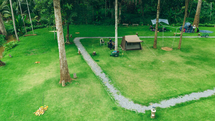 Top view of Tourists are camping on the green grass, under a big tree.