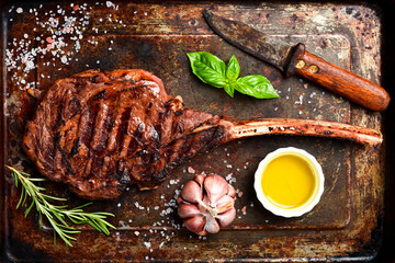 Steak on the bone. Grilled Tomahawk steak with rosemary and spices on a metal plate. Top view.
