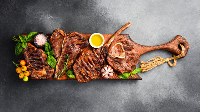 Variety of grill black Angus Prime meat steaks: Tomahawk, T-bone, Ribeye and Ossobuco. Top view. Rustic style.