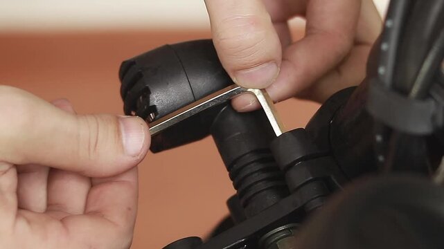 Using an allen hex wrench to tighten a screw of a motorcycle headlight by hand 