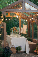 decorated greenhouse in trendy wedding setting with dinner table, candles and candle lights.