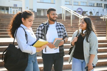 Three international students standing and holding a books