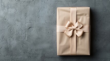 A beautifully wrapped gift with a soft ribbon on a textured gray background, perfect for celebration or special occasion.