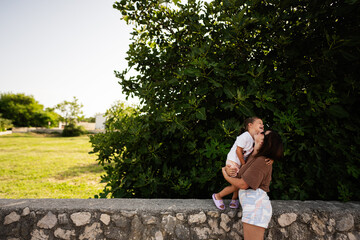 Mother lifting daughter in playful moment outside on a sunny day