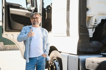 Happy confident male driver standing in front on his truck