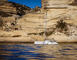 Catamaran anchored by a cliff in Corsica. 