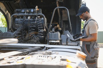 Truck repair service. African american Mechanic makes computer diagnostic of the semitruck