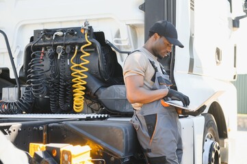 Truck repair service. African american Mechanic makes computer diagnostic of the semitruck